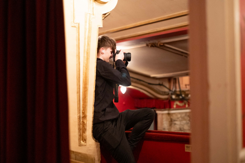 Student standing taking a photograph in the auditorium