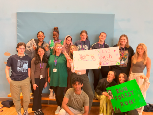 Group of Health and Social Care students wearing green holding supportive posters