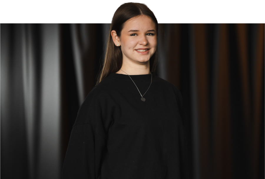 sophie in front of curtain smiling at the camera